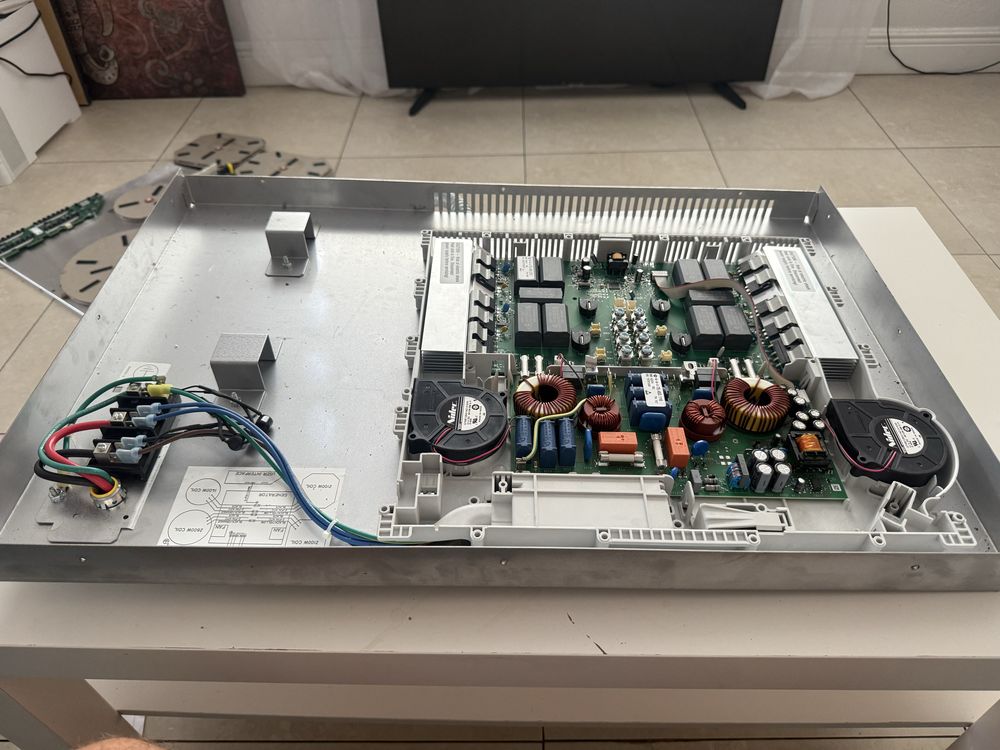 Opened induction cooktop chassis with exposed circuit boards and cooling fans.